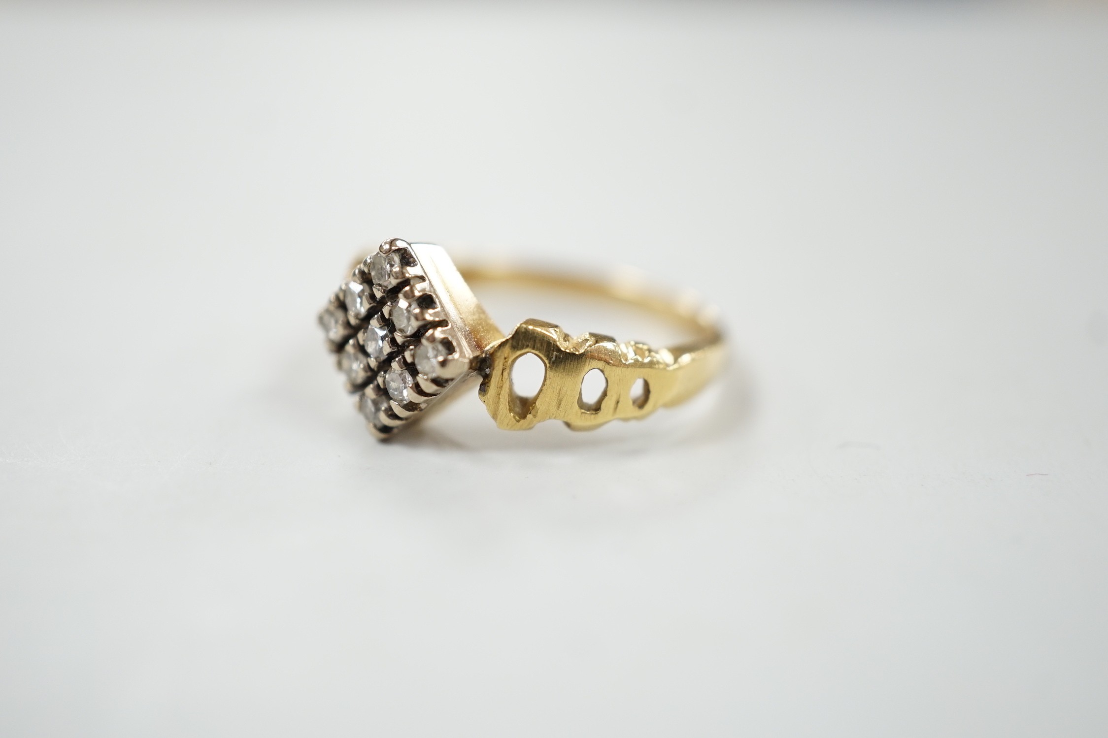 An 18ct and nine stone diamond set table ring, with pierced shoulders, size M/N, gross weight 3.7 grams.